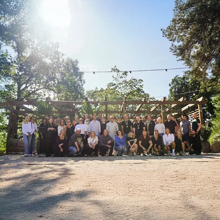 WeAudit-teamet samlade utomhus under en pergola en solig sommardag