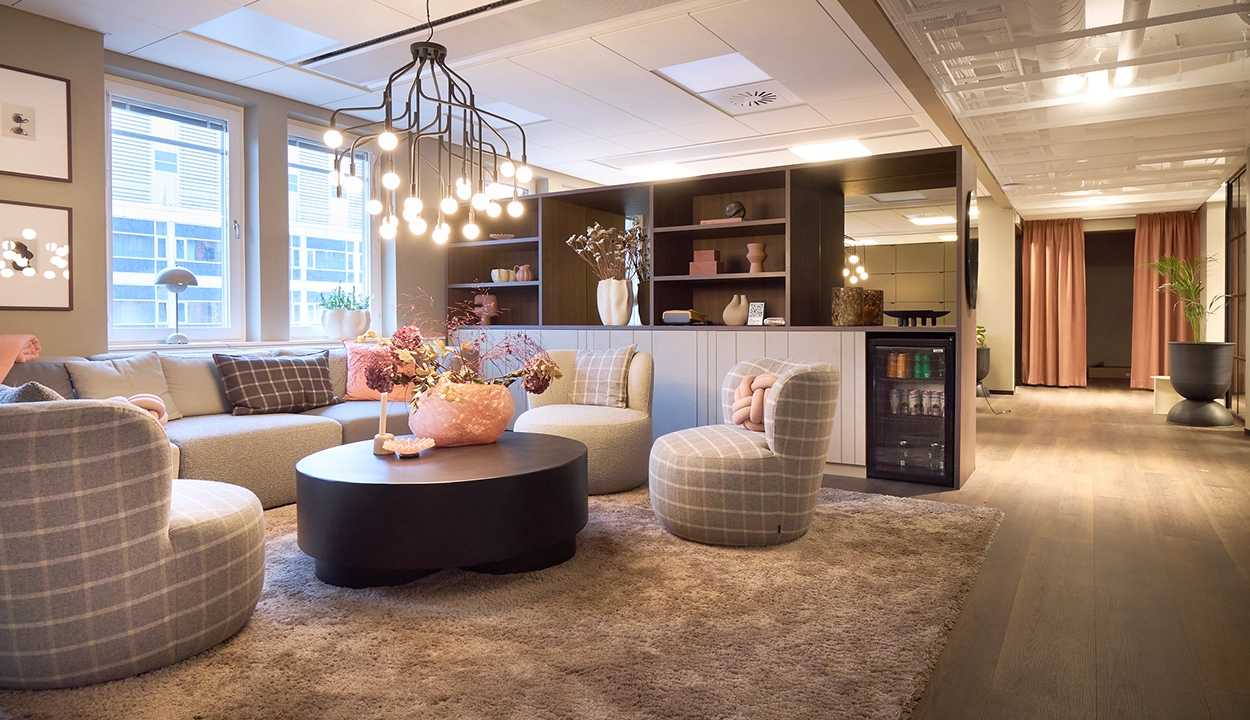 Loungeyta med modulsoffa, rund soffbord och pendellampa på WeAudits Stockholmskontor