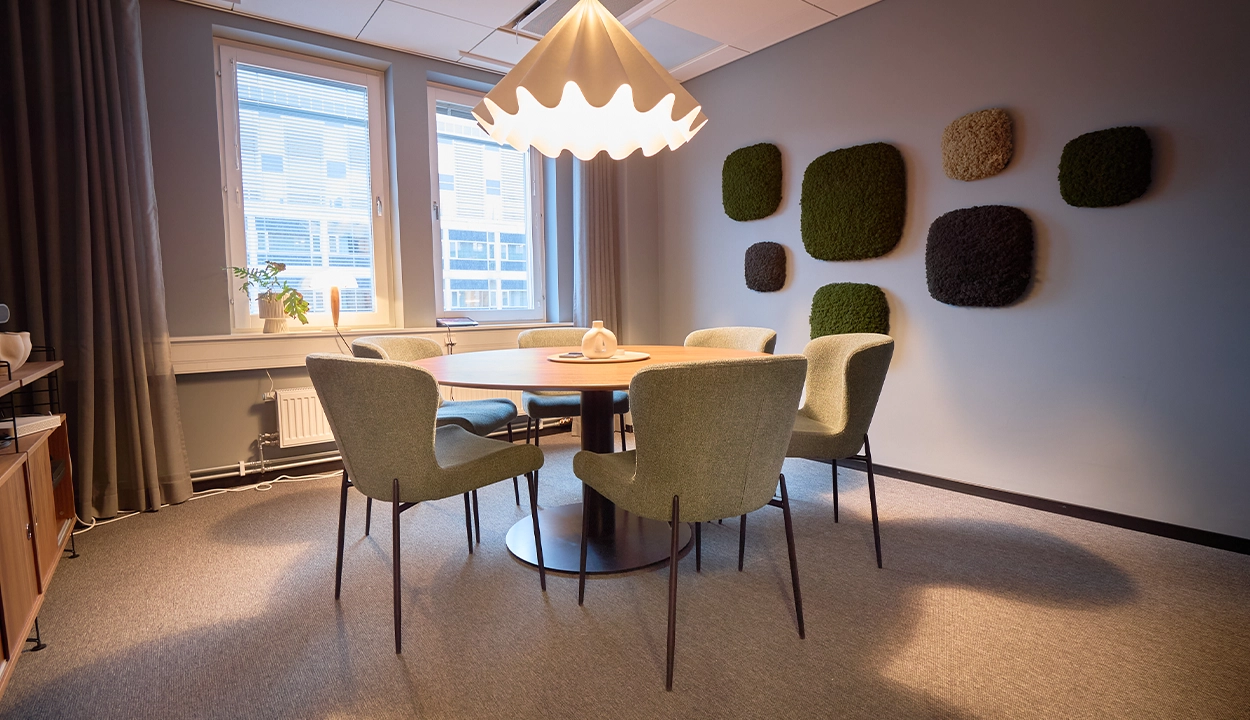Mindre mötesrum med runt bord och mossvägg på WeAudits Stockholmskontor